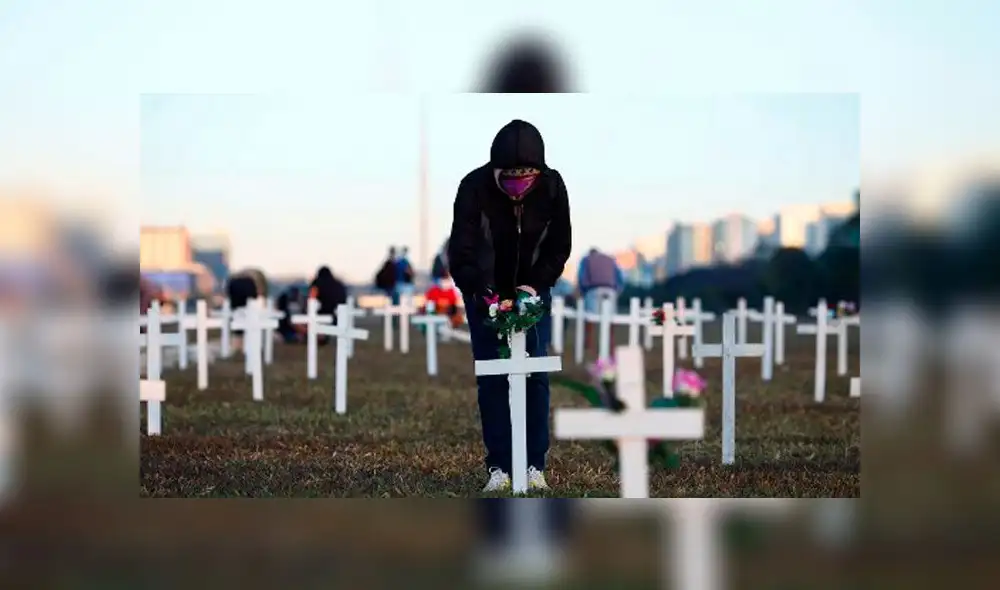 Un manifestante coloca flores en una cruz durante una protesta contra el presidente Jair Bolsonaro y en honor a las personas que murieron por la COVID-19. Foto: AFP. Un manifestante coloca flores en una cruz durante una protesta contra el presidente Jair Bolsonaro y en honor a las personas que murieron por la COVID-19. Foto: AFP.