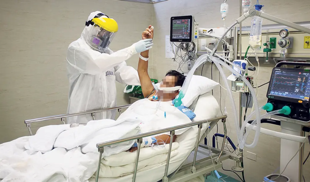 Jeanpierre Mendoza ayuda en terapia motriz a paciente Covid en el hospital de emergencias de Villa El Salvador. (Foto: Antonio Melgarejo)