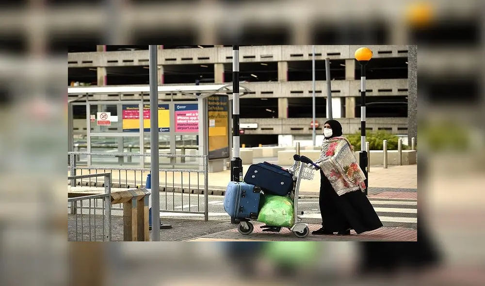 A passenger wearing PPE (personal protective equipment), including a face mask as a precautionary measure against COVID-19, pushes his luggage after arriving at Manchester Airport in northern England, on June 8, 2020, as the UK government's planned 14-day quarantine for international arrivals to limit the spread of the novel coronavirus begins. (Photo by Oli SCARFF / AFP) A passenger wearing PPE (personal protective equipment), including a face mask as a precautionary measure against COVID-19, pushes his luggage after arriving at Manchester Airport in northern England, on June 8, 2020, as the UK government's planned 14-day quarantine for international arrivals to limit the spread of the novel coronavirus begins. (Photo by Oli SCARFF / AFP)