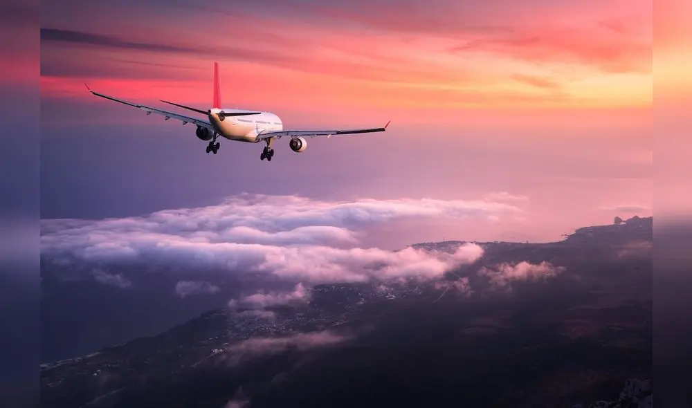 Airplane. Landscape with big white passenger airplane is flying in the red sky over the clouds at colorful sunset. Journey. Passenger airliner is landing at dusk. Business trip. Commercial plane Airplane. Landscape with big white passenger airplane is flying in the red sky over the clouds at colorful sunset. Journey. Passenger airliner is landing at dusk. Business trip. Commercial plane