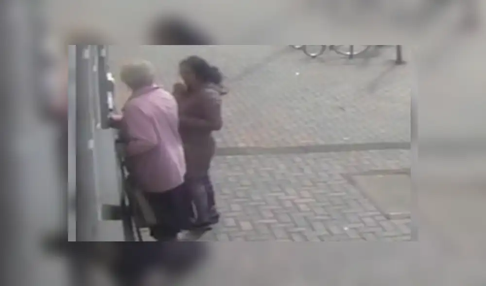 La delincuente se acercó silenciosamente a la anciana cuando estaba retirando dinero en un cajero automático La delincuente se acercó silenciosamente a la anciana cuando estaba retirando dinero en un cajero automático