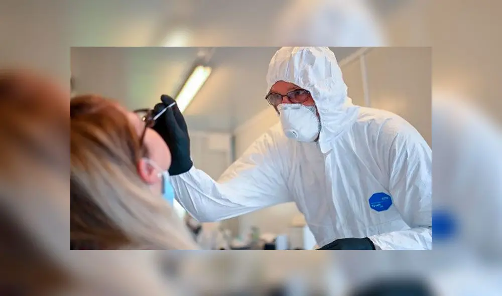Empleado de la salud en Alemania le toma una prueba a una mujer para descartar el coronavirus. Foto: AFP.