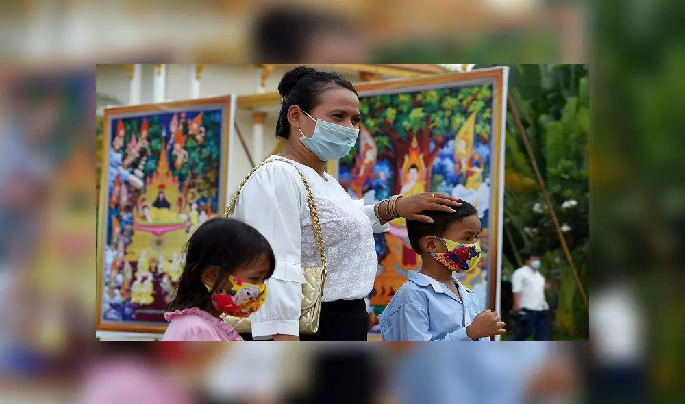 A woman and her children, wearing face masks as a preventive measure against the spread of the COVID-19 novel coronavirus, attend the Visak Bochea Buddhist celebration at a pagoda in Phnom Penh on May 6, 2020. - Buddhists commemorate the birth of Buddha, his attaining enlightenment and death on the day of the full moon in the month of May, which falls on May 6 this year. (Photo by TANG CHHIN Sothy / AFP)