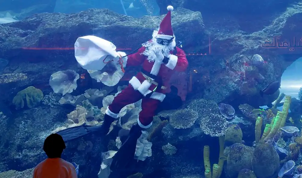 Hombre vestido como Papá Noel saluda a los visitantes del Aquarium de Dubái, en Emiratos Árabes Unidos. Foto: AFP
