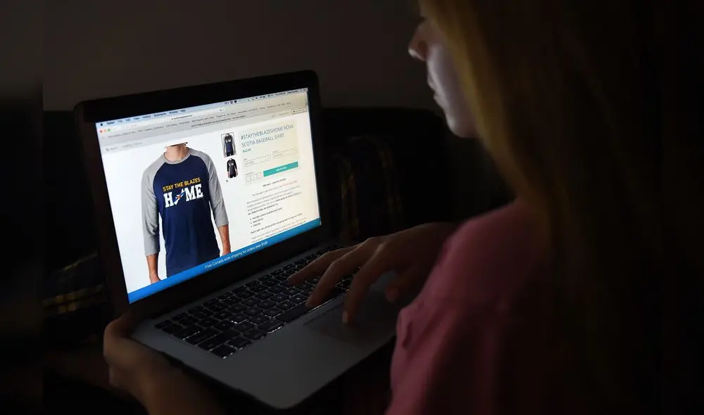 In this photo illustration, a person looks at a computer displaying a "Stay the blazes home" Nova Scotia baseball shirt on a website, April 16, 2020, in Arlington, Virginia. - "Stay the blazes home": the colloquial expletive-laced call by the premier of Canada's Atlantic coast province of Nova Scotia has become a rallying cry in the coronavirus pandemic fight.The comment during a televised COVID-19 briefing last week by Liberal Premier Stephen McNeil, exasperated by people who were ignoring a ban on public gatherings to stroll crowded beaches or go to parties, has since appeared on t-shirts and mugs. (Photo by Olivier DOULIERY / AFP) In this photo illustration, a person looks at a computer displaying a "Stay the blazes home" Nova Scotia baseball shirt on a website, April 16, 2020, in Arlington, Virginia. - "Stay the blazes home": the colloquial expletive-laced call by the premier of Canada's Atlantic coast province of Nova Scotia has become a rallying cry in the coronavirus pandemic fight.The comment during a televised COVID-19 briefing last week by Liberal Premier Stephen McNeil, exasperated by people who were ignoring a ban on public gatherings to stroll crowded beaches or go to parties, has since appeared on t-shirts and mugs. (Photo by Olivier DOULIERY / AFP)