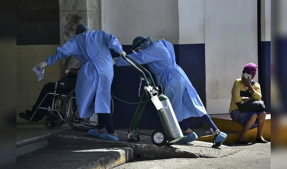 Trabajadores de la salud llevan a una persona,con oxígeno y en silla de ruedas, hacia las instalaciones de un hospital. Foto: AFP.