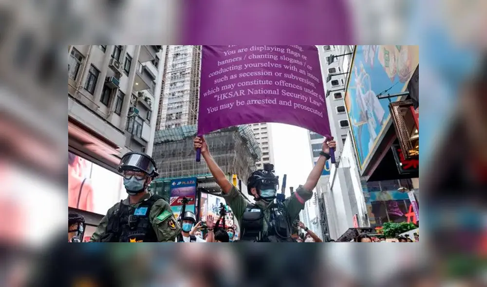Policía sostiene banderín en donde le dice a los manifestantes que están infringiendo la ley. Foto: Miguel Candela/Sopa Images