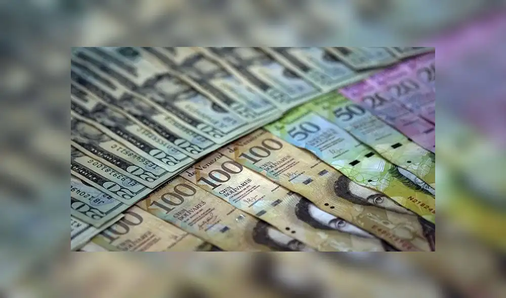 View of  local currency and US dollar banknotes, in Caracas on March 24, 2014. The Venezuelan government postponed another week the entry into force of the new exchange market announced more than a month ago to control the "black dollar", in a context of inflation and shortages, leading causes of the protests against President Nicolas Maduro which have so far caused 31 deaths.  AFP PHOTO/JUAN BARRETO (Photo by JUAN BARRETO / AFP)