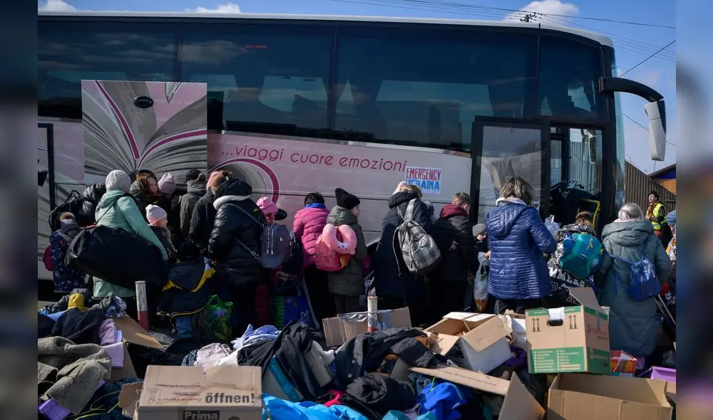 Ucranianos hacen cola para tomar un autobús directo a Italia después de cruzar la frontera hacia Polonia. Foto: referencial/AFP