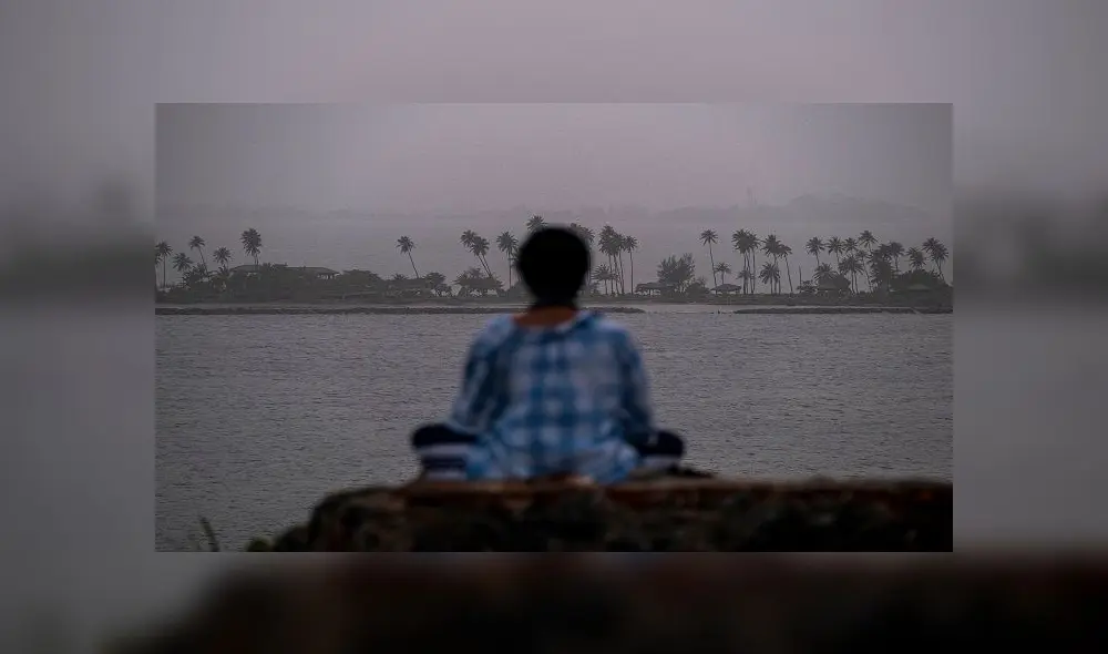 A woman meditates as a vast cloud of Sahara dust is blanketing the city of San Juan, Puerto Rico on June 22, 2020. - An expansive plume of dust from the Sahara is traveling westward across the Atlantic Ocean and is expected to reach the Caribbean and parts of the United States later this week. (Photo by Ricardo ARDUENGO / AFP)