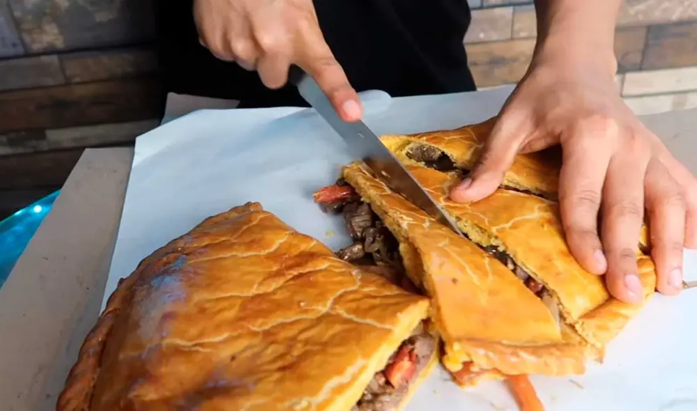 Desliza las imágenes para ver el aspecto que tiene este gigantesca empanada ofrecida en un local limeño. Foto: Captura de YouTube/Desbalanceados Desliza las imágenes para ver el aspecto que tiene este gigantesca empanada ofrecida en un local limeño. Foto: Captura de YouTube/Desbalanceados