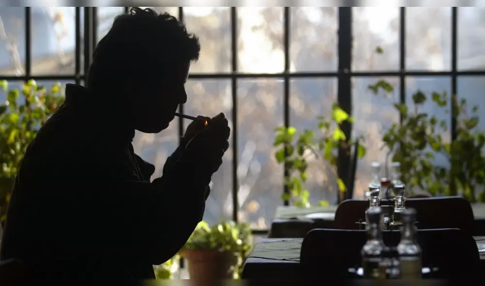 Un hombre enciende un cigarrillo en la zona reservada para fumadores de un restaurante en Santiago de Chile (julio 2005).. Un hombre enciende un cigarrillo en la zona reservada para fumadores de un restaurante en Santiago de Chile (julio 2005)..