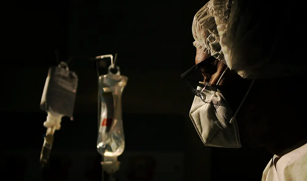 Médico revisa goteo intravenoso de uno de sus pacientes con COVID-19, en el hospital Oceanico en Niteroi, Río de Janeiro, Brasil. | Foto: Carl de Souza / AFP