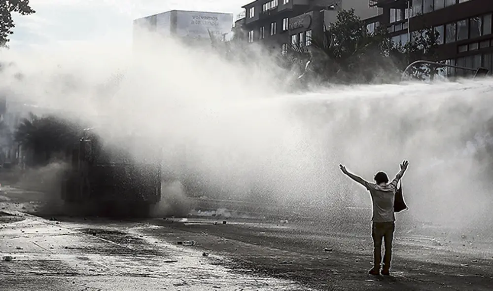En valiente actitud, joven manifestante soporta con firmeza el potente y hediondo chorro que le arroja el vehículo rompe manifestaciones. (Foto: Jorge Cerdán) En valiente actitud, joven manifestante soporta con firmeza el potente y hediondo chorro que le arroja el vehículo rompe manifestaciones. (Foto: Jorge Cerdán)