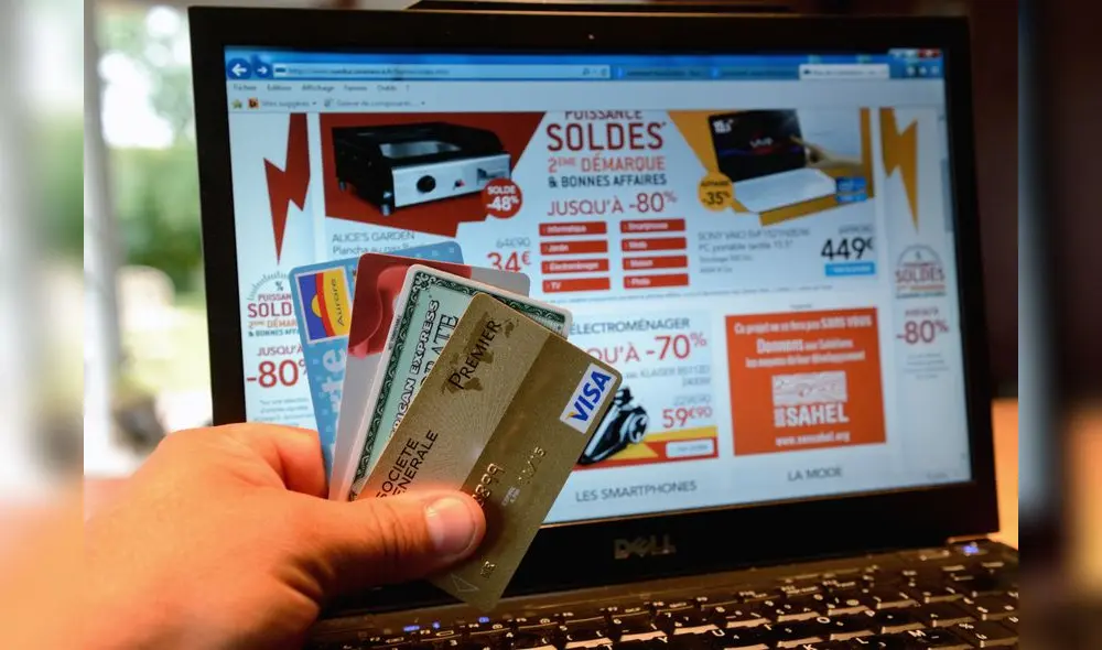 A person shows credit cards in front of a computer screen displaying electronics goods on sale on July 8, 2014 in Lille. AFP PHOTO / DENIS CHARLET (Photo by DENIS CHARLET / AFP)