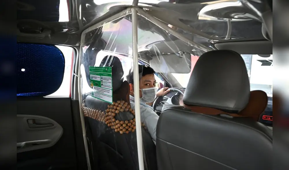 A taxi driver wearing a face mask looks on from behind a plastic screen as a preventive measure against the spread of COVID-19 novel coronavirus, in Hanoi on May 19, 2020. (Photo by Manan VATSYAYANA / AFP)