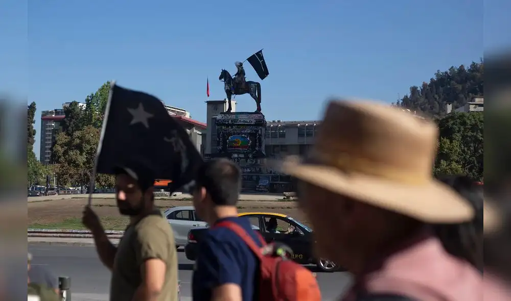 A tour guide (L) walks followed by tourists at Baquedano square in Santiago, Chile, on January 10, 2020. - A free walking tour of the "ground zero" of the protests seeks to explain, through street art, the genesis and evolution of the social uprising that has shaken Chile for the last three months. (Photo by CLAUDIO REYES / AFP) A tour guide (L) walks followed by tourists at Baquedano square in Santiago, Chile, on January 10, 2020. - A free walking tour of the "ground zero" of the protests seeks to explain, through street art, the genesis and evolution of the social uprising that has shaken Chile for the last three months. (Photo by CLAUDIO REYES / AFP)