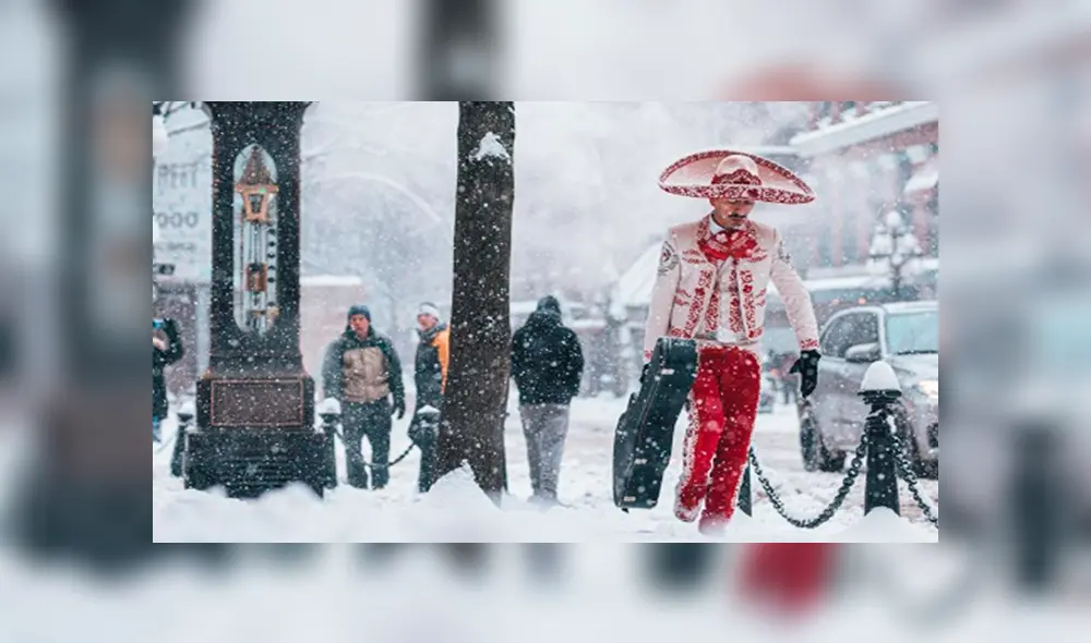 La fotografía tomada por Cameron Frazier captura a un mariachi cuyo atuendo color rojo contrasta con la blanca nieve mientras carga su guitarra.