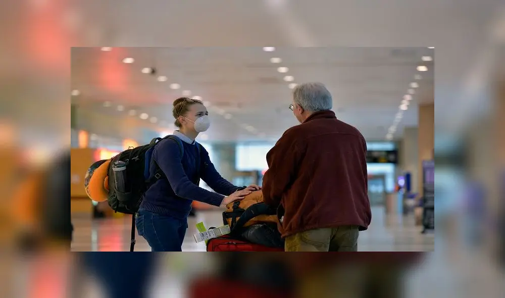 A women in a mask greets her father in the arrivals area at terminal E at Logan Airport in East Boston, Massachusetts on March 13, 2020. - US President Donald Trump declared the novel coronavirus, COVID-19, a national emergency on March 13, 2020. (Photo by Joseph Prezioso / AFP)