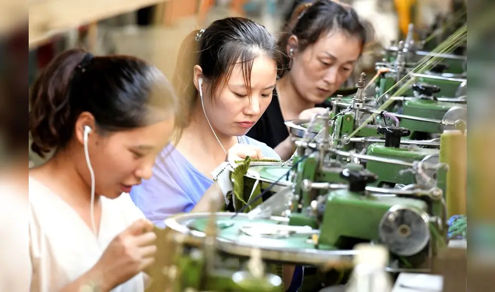 This photo taken on August 13, 2018 shows employees working on a production line of clothes for export at a factory in Xiayi county, in Shangqiu in China's central Henan province. - Key economic readings released on August 14 in China showed investment slumping to a record low for the first seven months of the year as retail sales slowed, pointing to weakness in the world's second largest economy. (Photo by STR / AFP) / China OUT