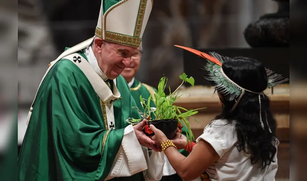 Pope Francis (L) receives a plant offered by an Amazon native as he celebrates the closing mass of the Synod on Amazonia on October 27, 2019 at the Saint Peter's Basilica in the Vatican. (Photo by Andreas SOLARO / AFP)