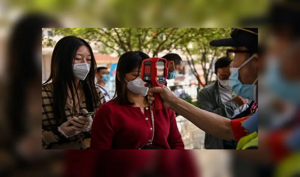 A worker wearing a face mask checks passengers body temperatures and a health code on their phones before they take a taxi after arriving at Hankou railway station in Wuhan, China's central Hubei province on May 12, 2020. - China reported no new domestic coronavirus infections on May 12, after two consecutive days of double-digit increases, including a new cluster over the weekend in Wuhan, which fuelled fears of a second wave of infections. (Photo by Hector RETAMAL / AFP) A worker wearing a face mask checks passengers body temperatures and a health code on their phones before they take a taxi after arriving at Hankou railway station in Wuhan, China's central Hubei province on May 12, 2020. - China reported no new domestic coronavirus infections on May 12, after two consecutive days of double-digit increases, including a new cluster over the weekend in Wuhan, which fuelled fears of a second wave of infections. (Photo by Hector RETAMAL / AFP)