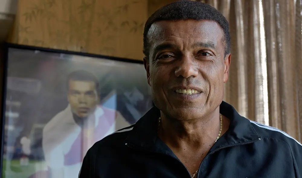 Teófilo Cubillas al lado de uno de sus cuadros vistiendo la camiseta de la selección peruana. | Foto: AFP