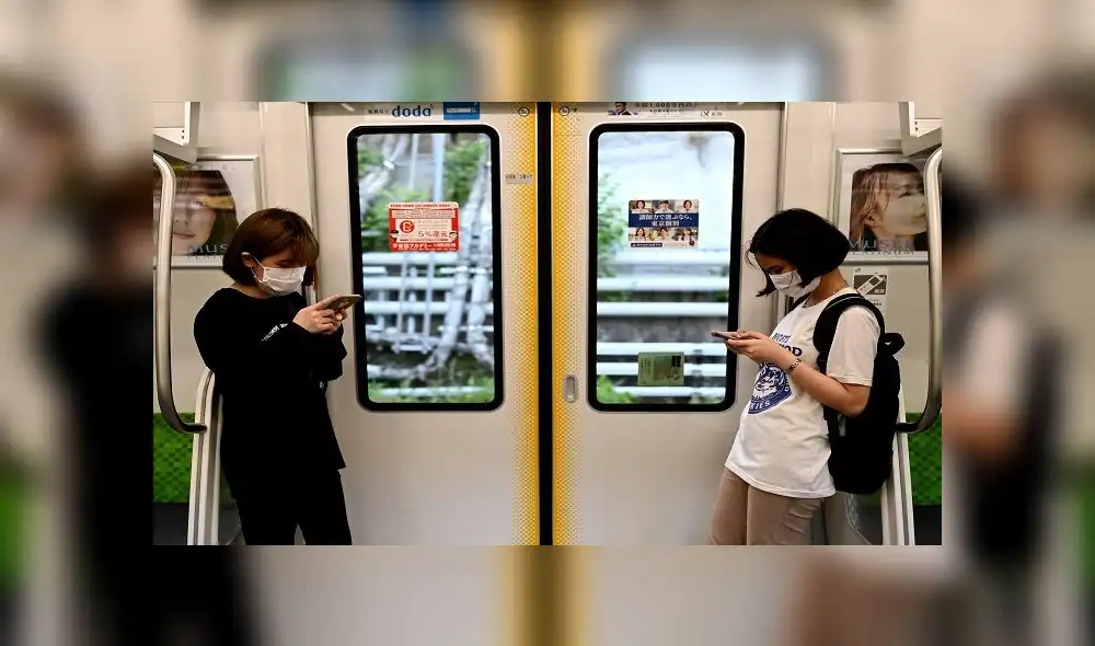 People wearing face masks amid concerns over spread of coronavirus (COVID-19) ride a train in Tokyo on Mau 24, 2020. - Prime Minister Shinzo Abe on May 21, 2020 lifted a state of emergency in several big cities in western Japan and hinted that the measure would be removed nationwide -- Tokyo and its neighbouring regions -- as early as next week. (Photo by Behrouz MEHRI / AFP)