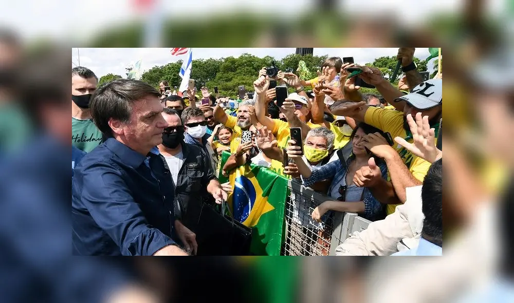 Brazil's President Jair Bolsonaro greets supporters upon arrival at Planalto Palace in Brasilia, on May 24, 2020, amid the COVID-19 coronavirus pandemic. - Despite positive signs elsewhere, the disease continued its surge in large parts of South America, with the death toll in Brazil passing 22,000 and infections topping 347,000, the world's second-highest caseload. (Photo by EVARISTO SA / AFP)