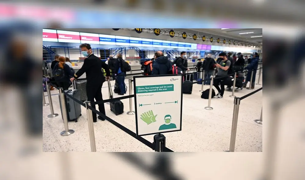 Passengers wearing PPE (personal protective equipment), including a face mask as a precautionary measure against COVID-19, socially distance as they queue at a check-in desk at Manchester Airport in northern England, on June 8, 2020, as the UK government's planned 14-day quarantine for international arrivals to limit the spread of the novel coronavirus begins. (Photo by Oli SCARFF / AFP) Passengers wearing PPE (personal protective equipment), including a face mask as a precautionary measure against COVID-19, socially distance as they queue at a check-in desk at Manchester Airport in northern England, on June 8, 2020, as the UK government's planned 14-day quarantine for international arrivals to limit the spread of the novel coronavirus begins. (Photo by Oli SCARFF / AFP)