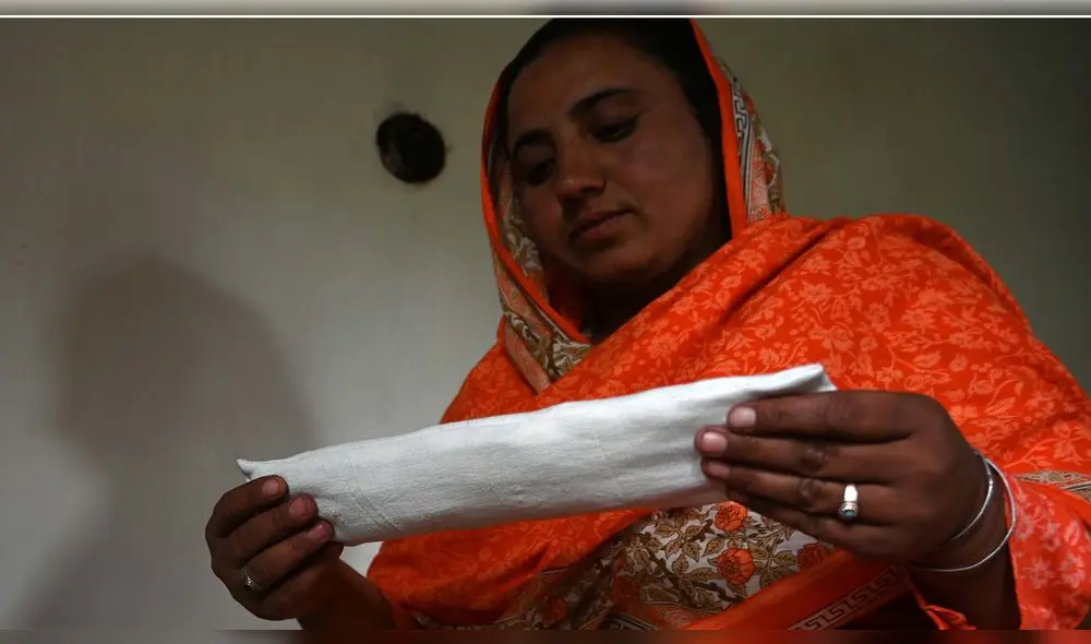 Hajra Bibi, mujer pakistaní, sostiene una compresa sanitaria que está haciendo con una máquina de coser en su casa en la aldea de Booni en Chitral.
