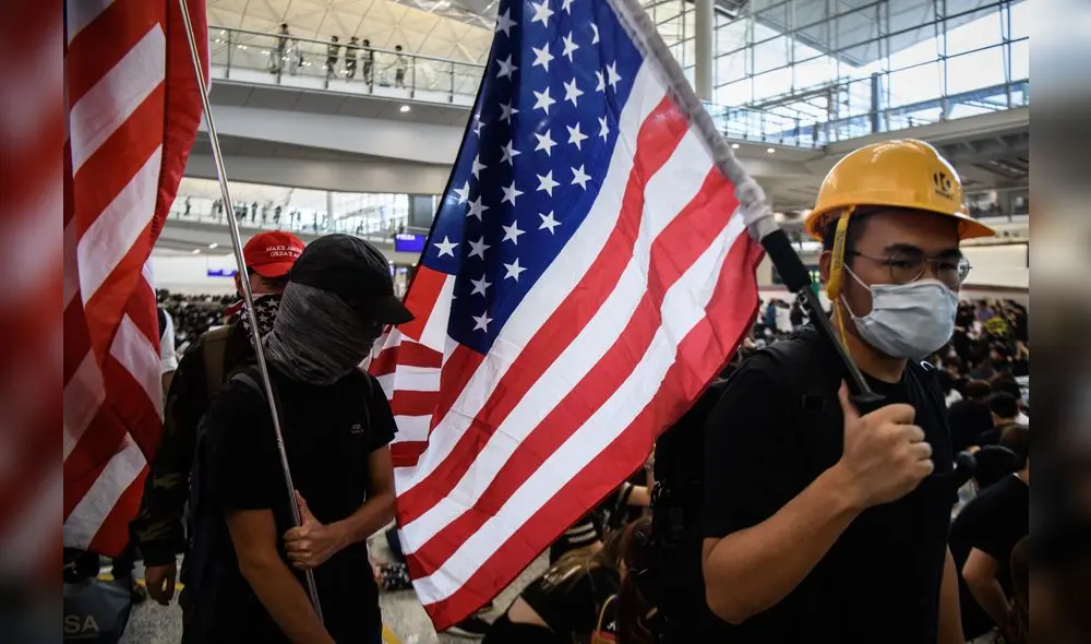 Manifestantes portan banderas de Estados en el aeropuerto internacional de Hong Kong. Manifestantes portan banderas de Estados en el aeropuerto internacional de Hong Kong.