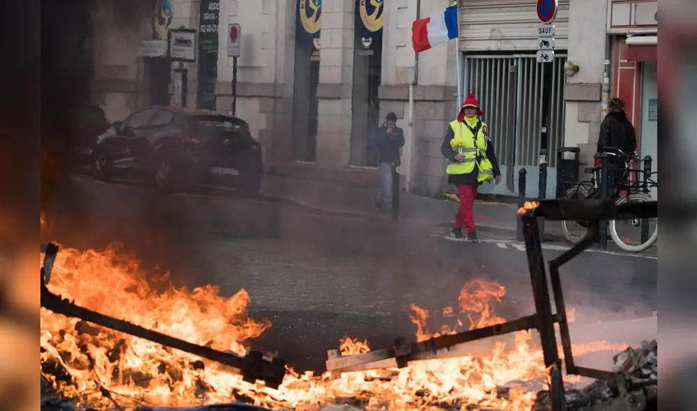 A demonstrator walks past burning debris during a protest called by the 'Yellow Vest' (gilets jaunes) anti-government movement as part of a nationwide multi-sector strike against the French government's pensions overhaul, on January 11, 2020 in Nantes, western France. - France's government on January 11, 2020, offered a possible compromise to unions waging a crippling, weeks-long transport strike against pension reform, offering to withdraw the most contested proposal that would in effect have raised the retirement age by two years. "To demonstrate my confidence in the social partners... I am willing to withdraw from the bill the short-term measure I had proposed" to set a so-called "pivot age" of 64 with effect from 2027, Prime Minister Edouard Philippe wrote in a letter to union leaders a day after they met seeking to end the labour action, now in its 38th day. (Photo by Loic VENANCE / AFP) A demonstrator walks past burning debris during a protest called by the 'Yellow Vest' (gilets jaunes) anti-government movement as part of a nationwide multi-sector strike against the French government's pensions overhaul, on January 11, 2020 in Nantes, western France. - France's government on January 11, 2020, offered a possible compromise to unions waging a crippling, weeks-long transport strike against pension reform, offering to withdraw the most contested proposal that would in effect have raised the retirement age by two years. "To demonstrate my confidence in the social partners... I am willing to withdraw from the bill the short-term measure I had proposed" to set a so-called "pivot age" of 64 with effect from 2027, Prime Minister Edouard Philippe wrote in a letter to union leaders a day after they met seeking to end the labour action, now in its 38th day. (Photo by Loic VENANCE / AFP)
