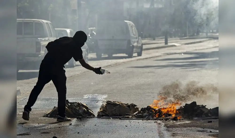 Un manifestante se prepara para encender una hoguera durante los enfrentamientos con la policía antidisturbios. Foto: AFP