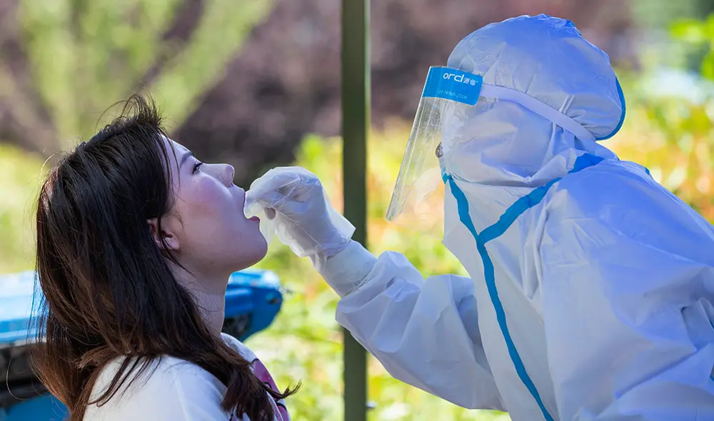 Personal de la salud toma una muestra de hisopado para analizar la COVID-19 en la Universidad de Wuhan, China. | Foto: STR / AFP