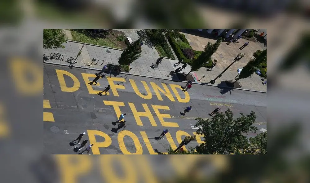 WASHINGTON, DC - JUNE 08: People walk down 16th street after Defund The Police was painted on the street near the White House on June 08, 2020 in Washington, DC. After days of protests in DC over the death of George Floyd, DC Mayor Muriel Bowser has renamed that section of 16th street "Black Lives Matter Plaza".   Tasos Katopodis/Getty Images/AFP
