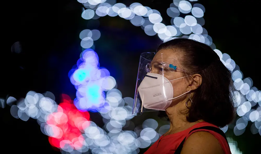 Una mujer usa mascarilla en una plaza decorada con luces navideñas en Caracas (Venezuela), donde hay disponibles bonos en el sistema Patria. Foto: EFE Una mujer usa mascarilla en una plaza decorada con luces navideñas en Caracas (Venezuela), donde hay disponibles bonos en el sistema Patria. Foto: EFE