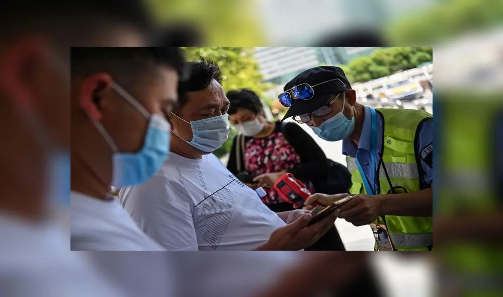 A worker wearing a face mask checks passengers body temperatures and a health code on their phones before they take a taxi after arriving at Hankou railway station in Wuhan, China's central Hubei province on May 12, 2020. - China reported no new domestic coronavirus infections on May 12, after two consecutive days of double-digit increases, including a new cluster over the weekend in Wuhan, which fuelled fears of a second wave of infections. (Photo by Hector RETAMAL / AFP) A worker wearing a face mask checks passengers body temperatures and a health code on their phones before they take a taxi after arriving at Hankou railway station in Wuhan, China's central Hubei province on May 12, 2020. - China reported no new domestic coronavirus infections on May 12, after two consecutive days of double-digit increases, including a new cluster over the weekend in Wuhan, which fuelled fears of a second wave of infections. (Photo by Hector RETAMAL / AFP)
