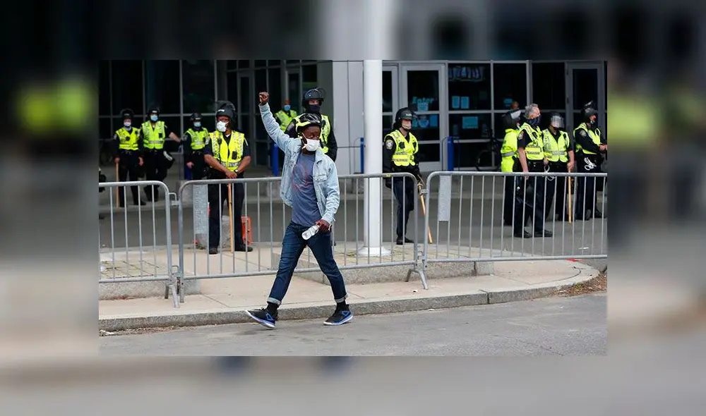 Un protestante pasa al frente de un cordón de policías puesto en la localidad de Boston, en otra manifestación tras la muerte de George Floyd. Foto: EFE