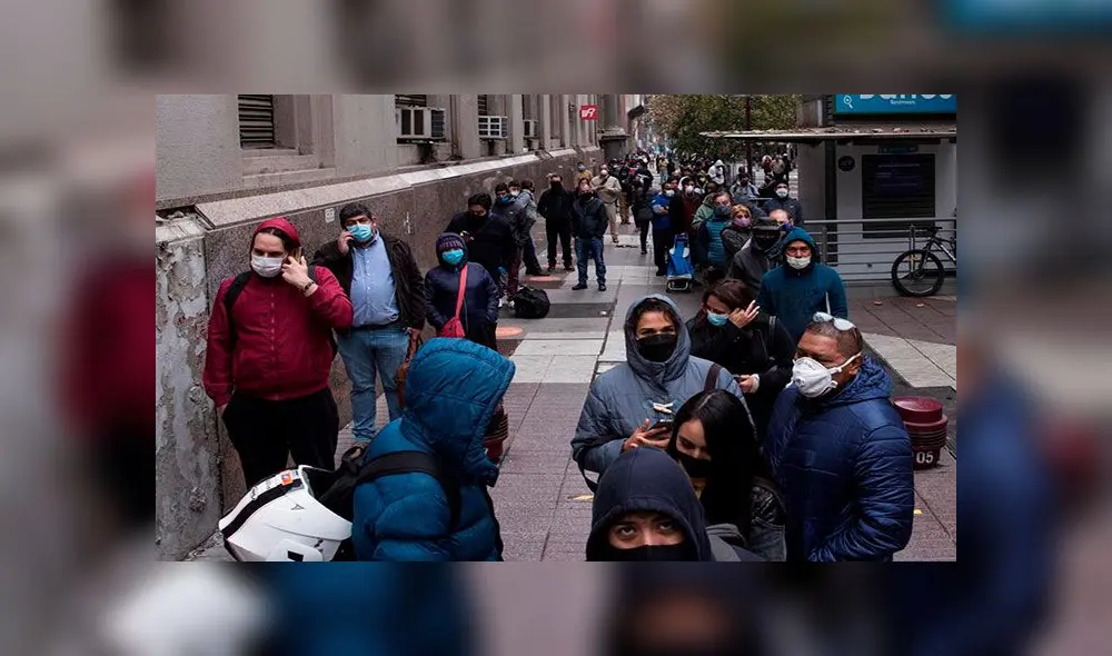 Un grupo de personas hace fila para acceder a un banco en el centro de Santiago, Chile.
