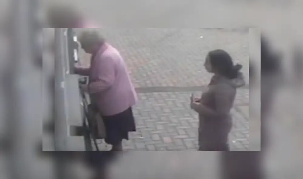La delincuente se acercó silenciosamente a la anciana cuando estaba retirando dinero en un cajero automático La delincuente se acercó silenciosamente a la anciana cuando estaba retirando dinero en un cajero automático