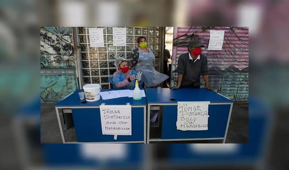 Volunteers wait, next to signs reading �Keep distance. Only with face masks�, for residents to come and take away lunches at a soup kitchen in La Pintana neighborhood, Santiago, on May 25, 2020, amid the new coronavirus pandemic. - Chile began Friday the delivery of 2.5 million boxes of basic products for the most vulnerable families amid protests due to food and job shortages caused by the measures imposed by the government against the new coronavirus pandemic. (Photo by MARTIN BERNETTI / AFP) Volunteers wait, next to signs reading �Keep distance. Only with face masks�, for residents to come and take away lunches at a soup kitchen in La Pintana neighborhood, Santiago, on May 25, 2020, amid the new coronavirus pandemic. - Chile began Friday the delivery of 2.5 million boxes of basic products for the most vulnerable families amid protests due to food and job shortages caused by the measures imposed by the government against the new coronavirus pandemic. (Photo by MARTIN BERNETTI / AFP)
