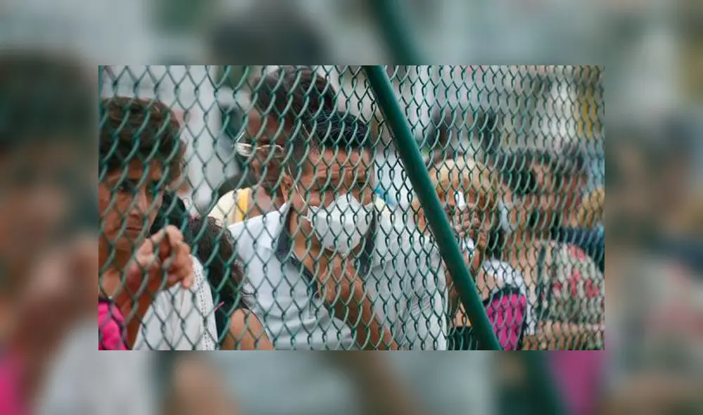 Un hombre con una mascarilla realiza una fila junto a otras personas en Guayaquil, Ecuador. Foto: EFE.