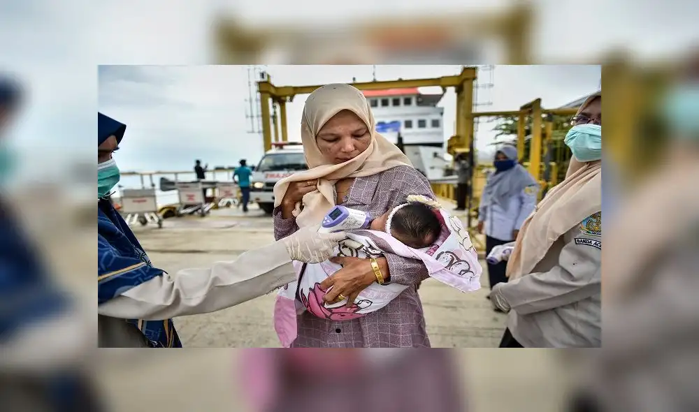 A health officer checks the body temperature of passengers, amid the COVID-19 coronavirus pandemic, as they get off a ferry at Ulee Lheue port in Banda Aceh on May 26, 2020. (Photo by CHAIDEER MAHYUDDIN / AFP) A health officer checks the body temperature of passengers, amid the COVID-19 coronavirus pandemic, as they get off a ferry at Ulee Lheue port in Banda Aceh on May 26, 2020. (Photo by CHAIDEER MAHYUDDIN / AFP)