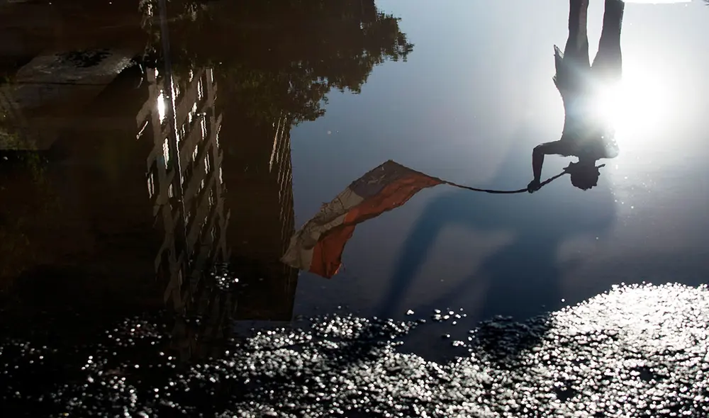 Vista del reflejo de un manifestante mientras ondea una bandera chilena durante una protesta en la Plaza Italia este viernes 30 de octubre, días después del histórico plebiscito. Foto: EFE