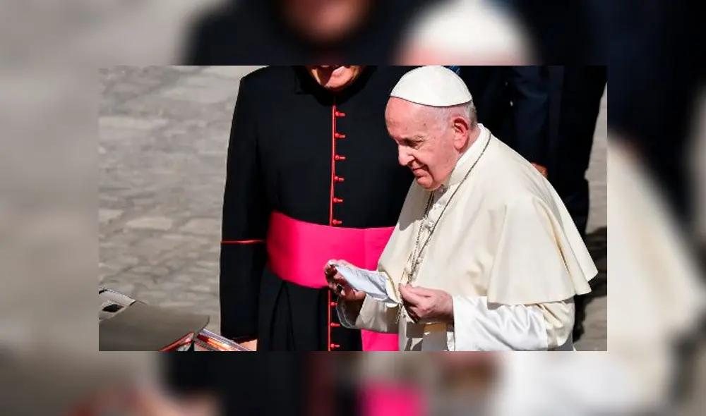 El Papa Francisco sostiene su mascarilla cuando se va al final de una audiencia pública limitada. Foto: AFP.