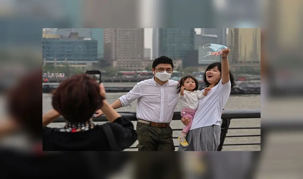 People wearing face masks pose for a photo while visiting the promenade on the Bund along the Huangpu River during a holiday on May Day, or International Workers' Day, in Shanghai on May 1, 2020. - With optimism and a heavy dose of caution, millions of Chinese hit the road or visited newly re-opened tourist sites on May 1 for an extended national holiday in a post-coronavirus confidence test. (Photo by Hector RETAMAL / AFP)