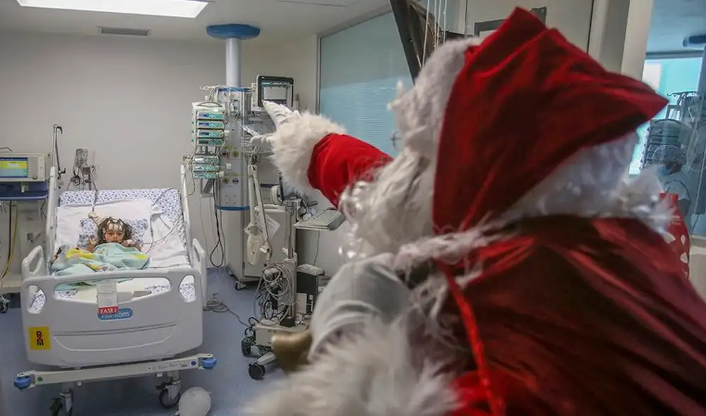 Profesional de la salud vestido de Papá Noel saluda a un niño hospitalizado en Cali, Colombia. Foto: AFP