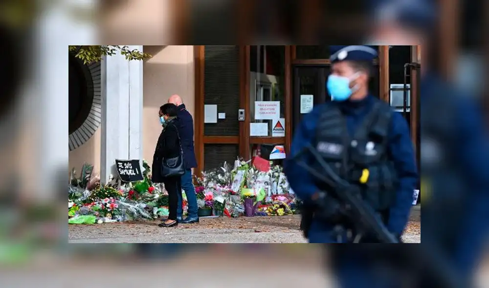 Gente mira las flores colocadas fuera de la escuela secundaria Bois d'Aulne en homenaje al maestro de historia. Foto: AFP Gente mira las flores colocadas fuera de la escuela secundaria Bois d'Aulne en homenaje al maestro de historia. Foto: AFP