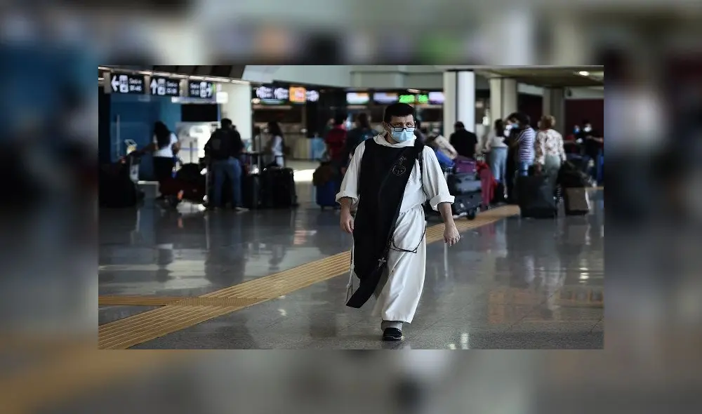 A monk walks across a terminal as people check in at Rome's Fiumicino airport on June 3, 2020, as airports and borders reopen for tourists and residents free to travel across the country, within the COVID-19 infection, caused by the novel coronavirus. (Photo by Filippo MONTEFORTE / AFP)